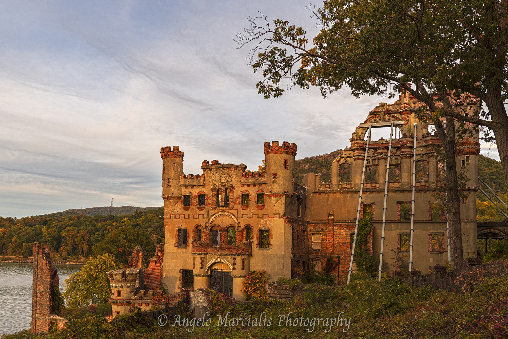 Bannerman Castle ruins overlooking the Hudson River at Pollepel Island, New York, during autumn evening light, featuring crumbling stone towers, Gothic architecture, and surrounding forested Highlands landscape.