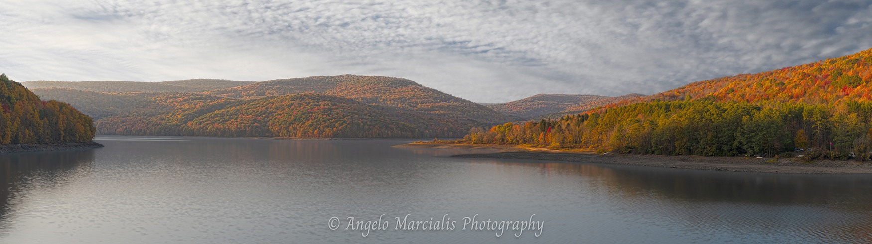 Fine art landscape photograph of the Pepacton Reservoir in the Catskills, New York, featuring tranquil water, colorful fall foliage, rolling mountain ridges, and soft morning light under textured clouds.