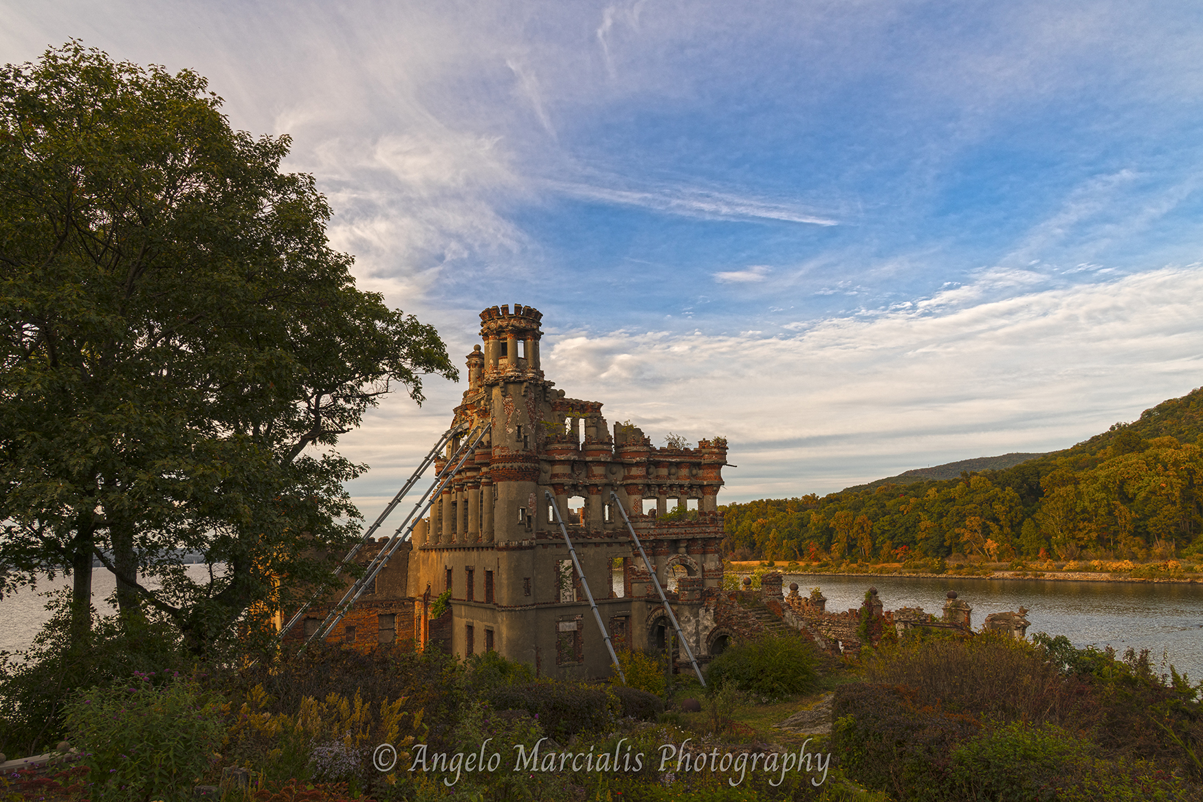 Warm evening light reveals the weathered beauty of Bannerman Castle as the historic Hudson River landmark stands against a backdrop of autumn color and dramatic skies in New York's Hudson Highlands.